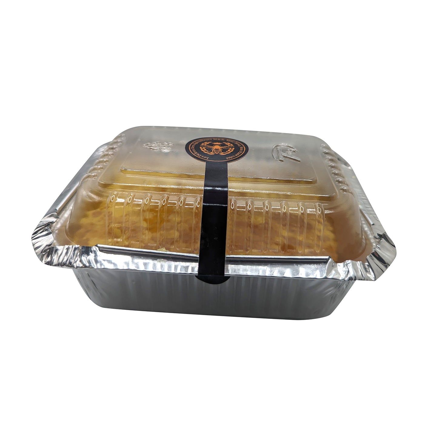 A rectangular foil container with a transparent plastic lid, sealed with a black band. The lid has a black and orange circular logo on top. Likely for food storage or delivery, the container could hold Quebec Gold: Pure Honey Comb Straight from Nature's Hive by Mielbrut.com or something else delightful; contents are not clearly visible.