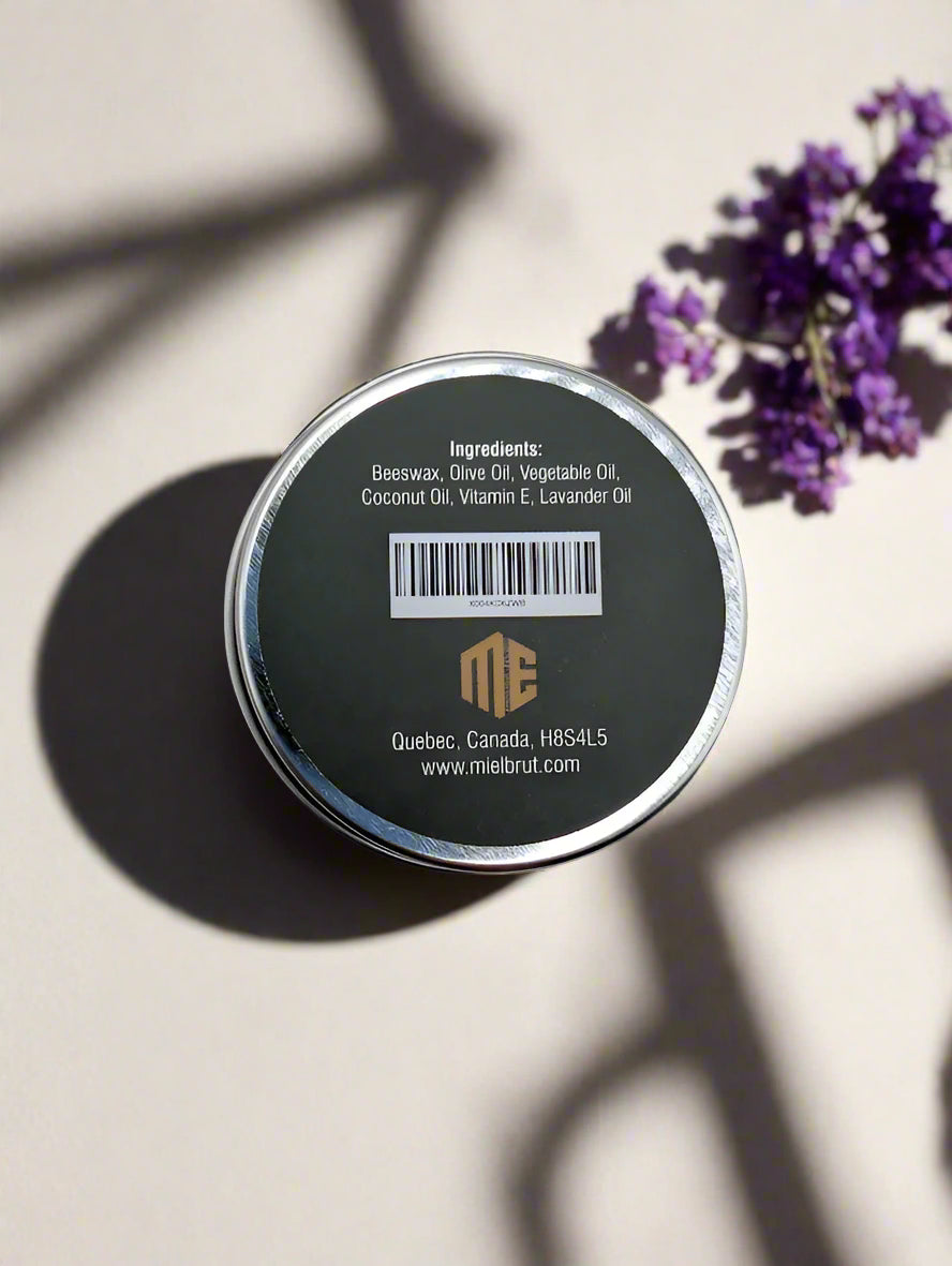 A top view of the "Lavender Beeswax Balm 1oz - Soothing beeswax and relaxing lavender" by Mielbrut.com highlights its natural ingredients: beeswax, olive oil, vegetable oil, coconut oil, vitamin E, and lavender oil for dry skin. The label also shows a Quebec address and website URL.