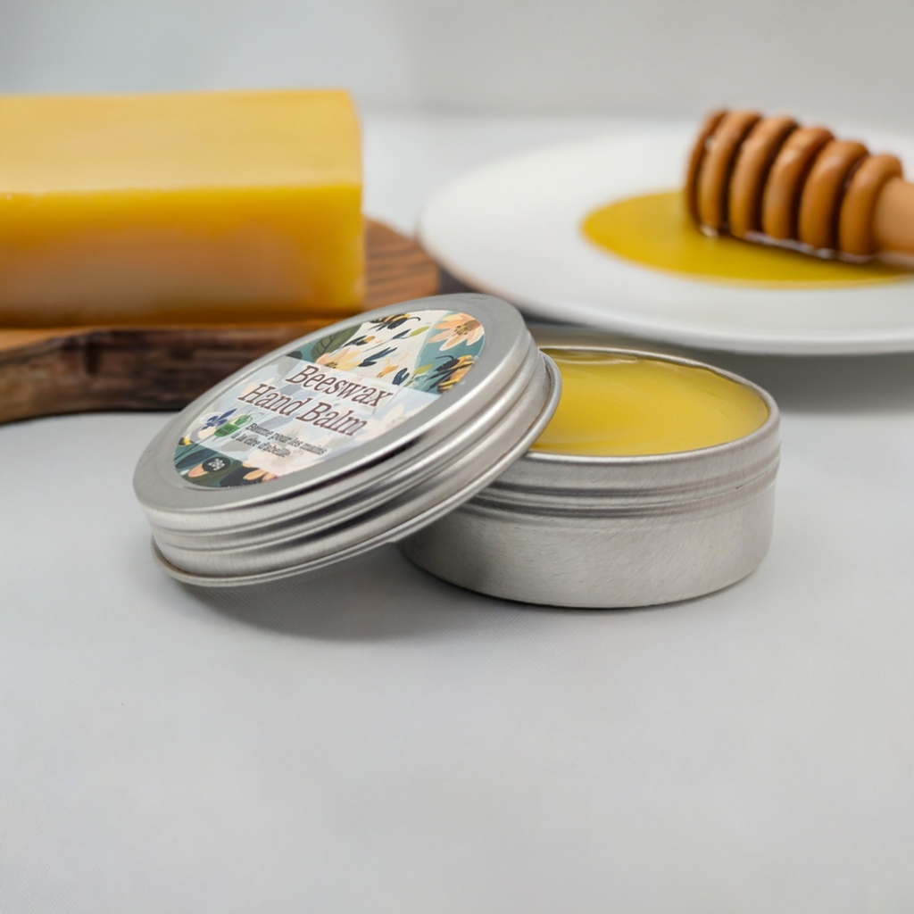A tin of Mielbrut.com's Beeswax Balm: Moisturizer for lips, hands, feet and skin with the lid partially open, showcasing the yellow balm inside. Behind it is a rectangular block of beeswax and a plate with a wooden honey dipper and a pool of honey. The background is white, creating a clean aesthetic.