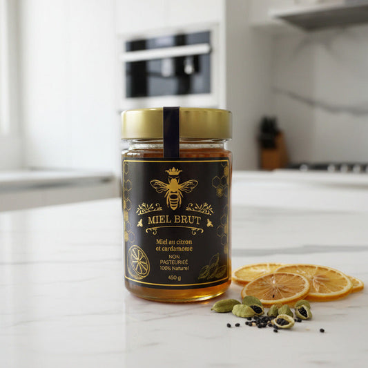 Jar of Miel Brut honey on a kitchen counter with dried lemons and cardamom pods.