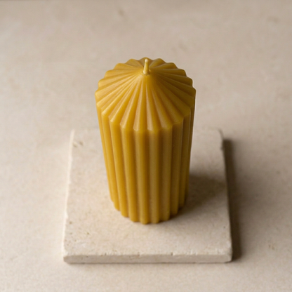 Ribbed beeswax pillar candle on a square stone base
