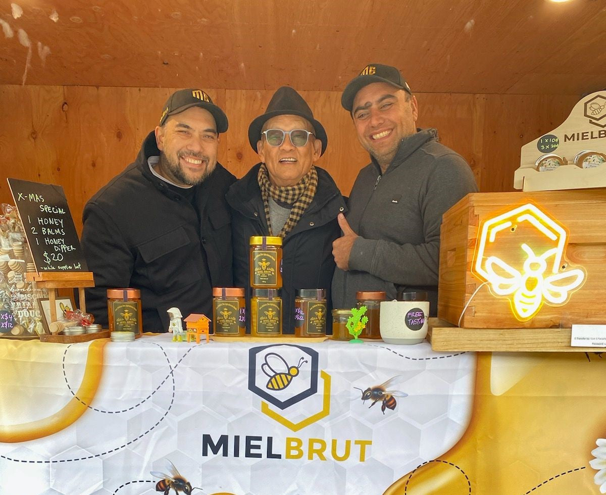 L'équipe Mielbrut à son kiosque d'un marché de Noël, avec des pots de miel brut