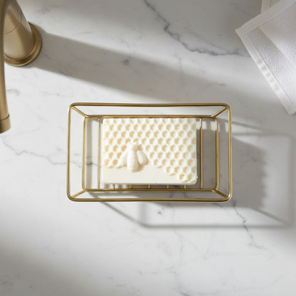 Bar of soap with a honeycomb pattern on a golden soap holder in a modern bathroom counter.